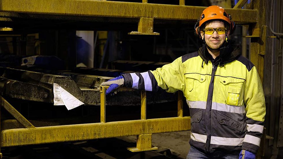 Kaivostyöntekijä katsoo kameraan hymyillen. 