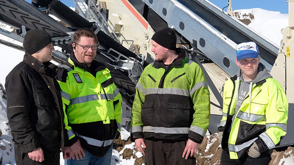 Neljä miestä työmaalla Lokotrack ST4.8-kolmitasoseulan edessä.