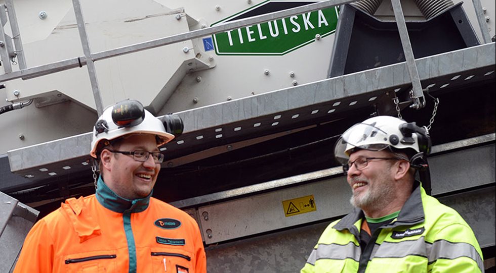 Kaksi hymyilevää miestä seulan vieressä.