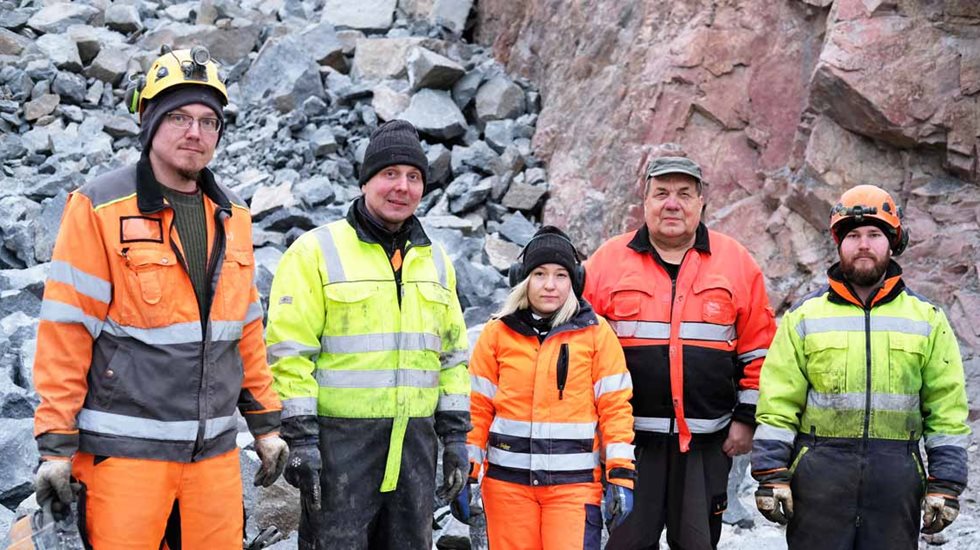 Neljä miestä ja yksi nainen louhoksella kivien edessä.