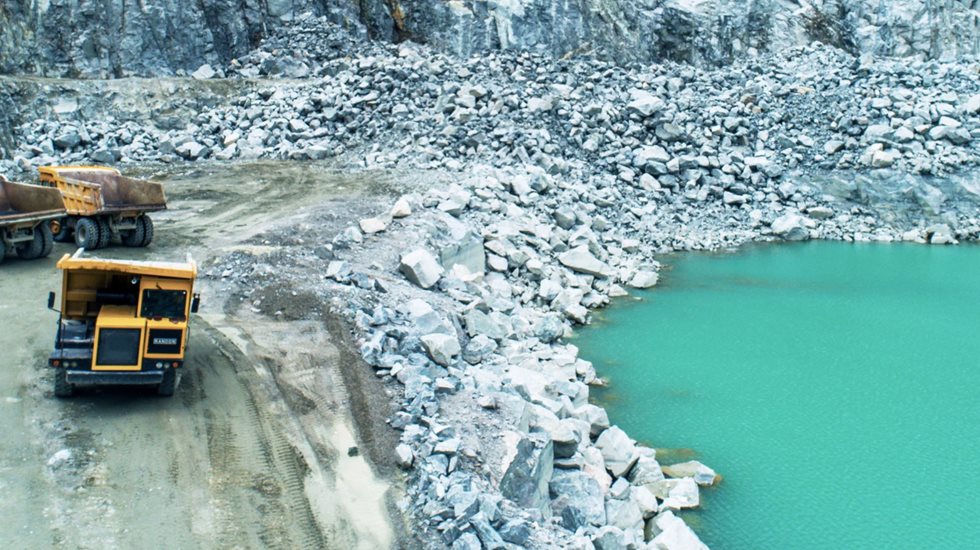 Two trucks next to turquoise pond 