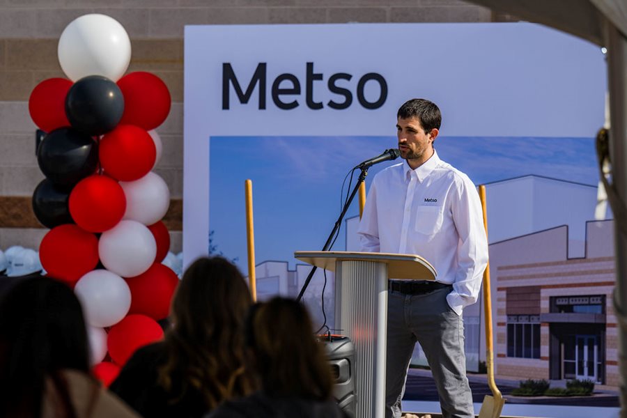 Man wearing white shirt speaking into a microphone in front of a podium