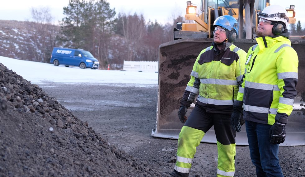 Two men looking at a pile of crushed asphalt.