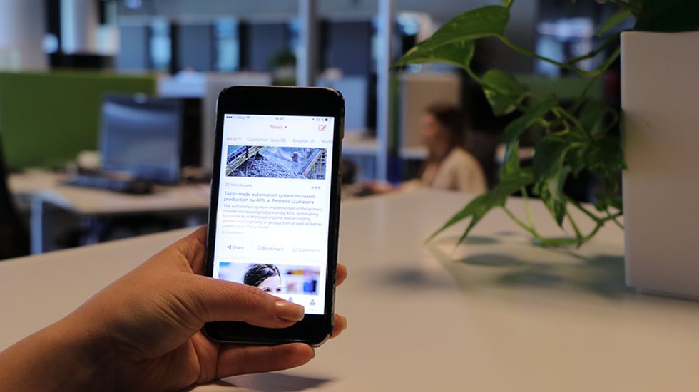 Henkilö pitelee käsissään älypuhelinta toimistotilassa.