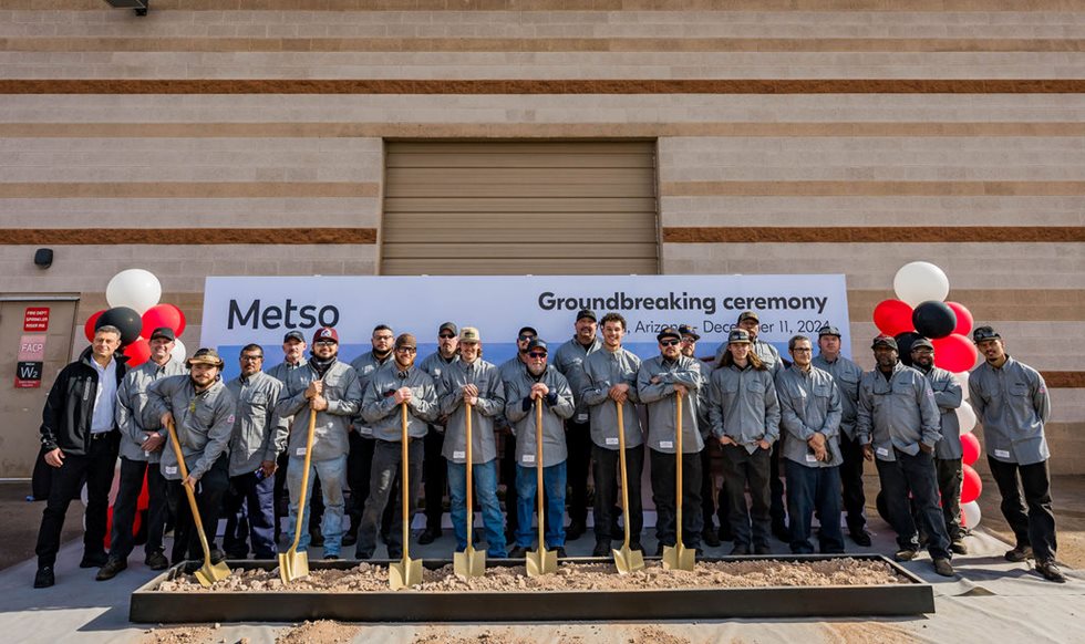 Group of men in blue uniforms holding shovels at a ground breaking ceremony
