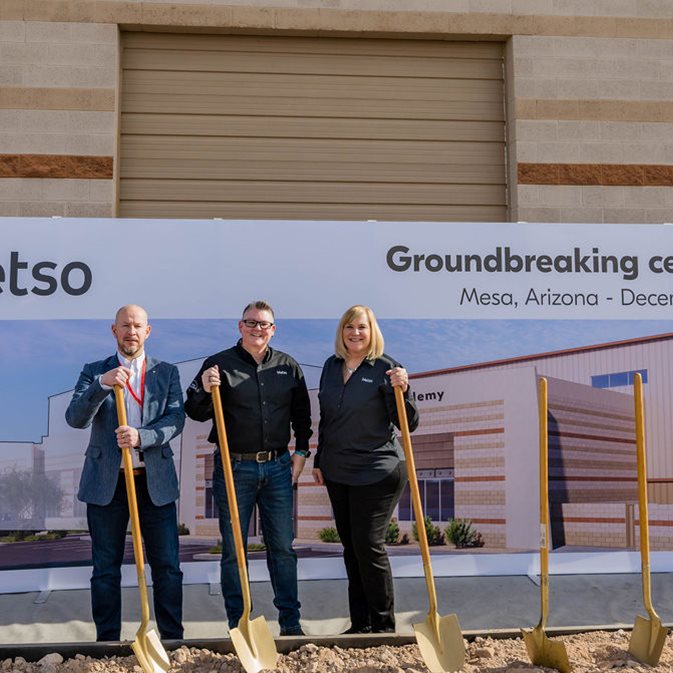 Three people standing in front of a backdrop, holding shovels at a groundbreaking ceremony