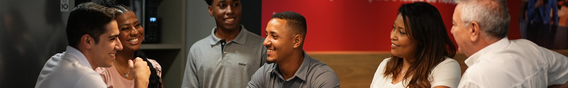 Three Metso employees sitting at an desk and smiling in front of a laptop.