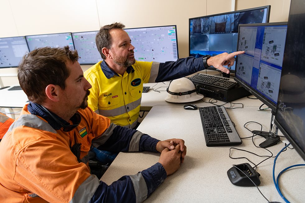 Two men looking at the monitoring screen of a quarry. 