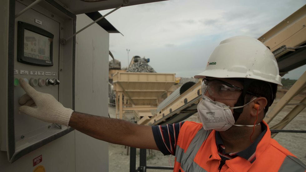 A man at a quarry handling the control buttons of mobile crushing equipment. 
