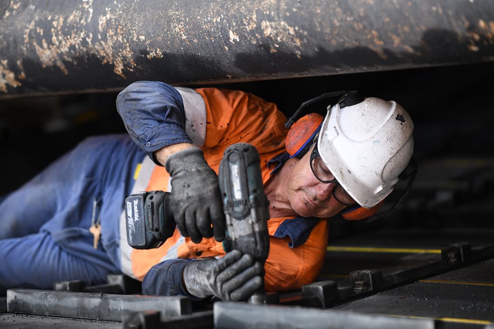 A man using a screwdrive during screen maintenance activities.