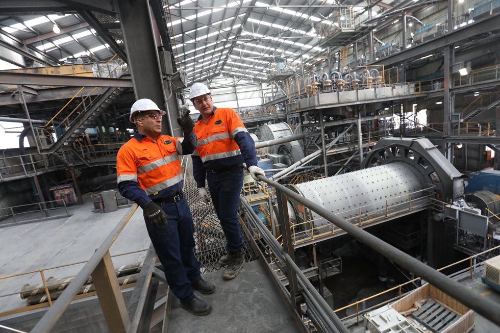 Two Metso employers talking next to a mill at Savage River facility.