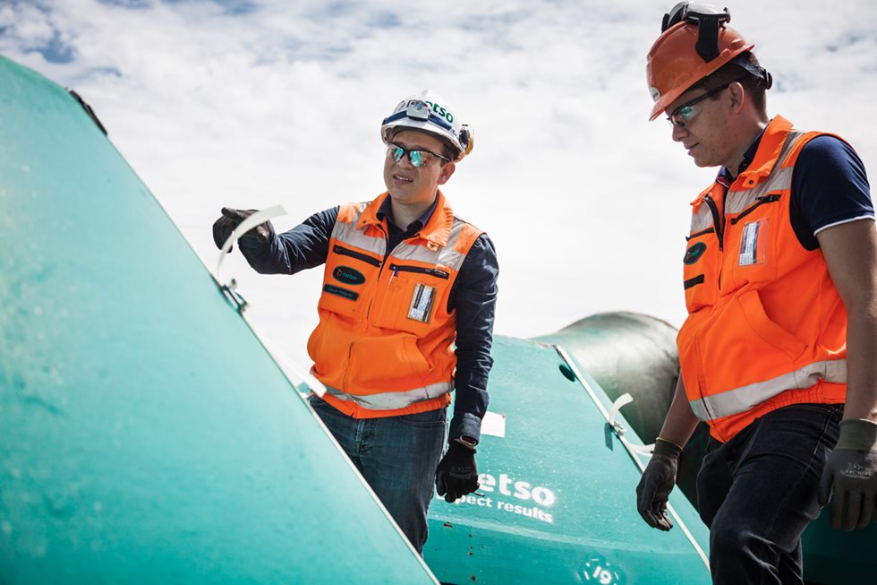 Two men looking at a crusher liner outside. 