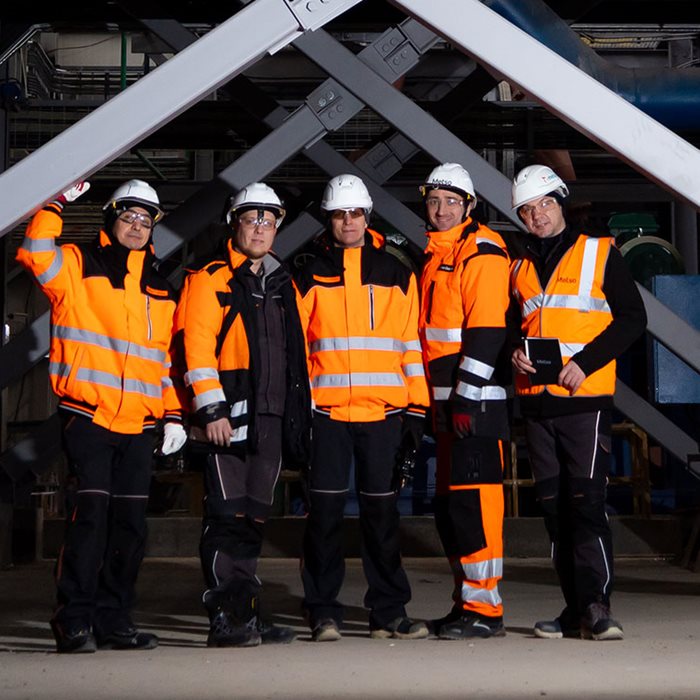 Man in working gear and helmet smiling at the camera.