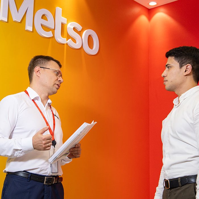 Two women with work gear looking at folder in their hands.