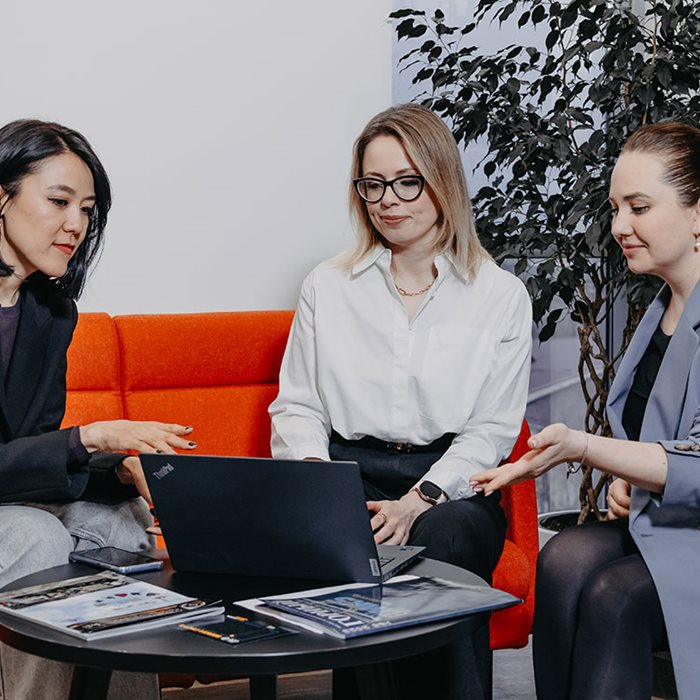 Three colleagues looking at a laptop.